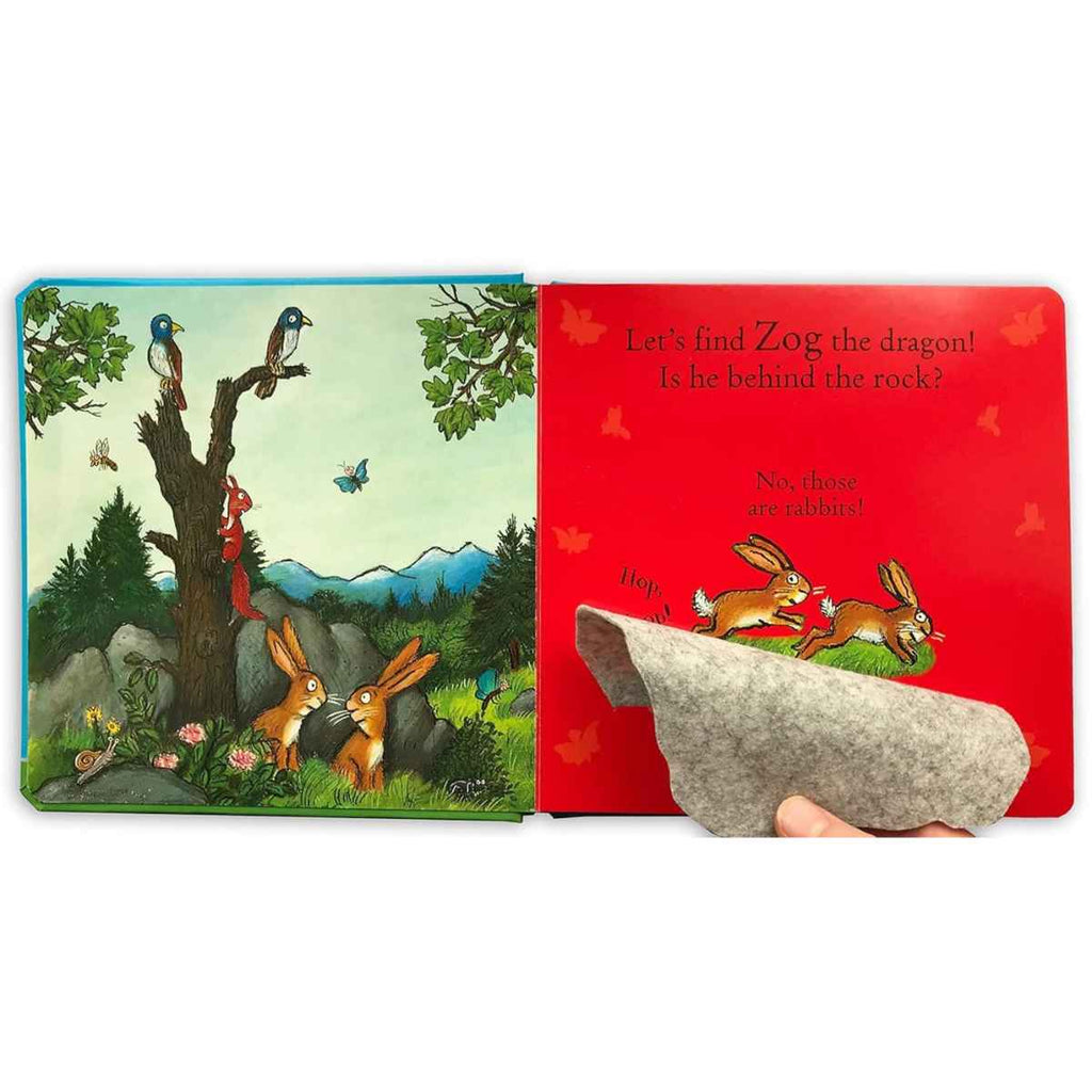 On the left page, a tall, bare tree stands in the middle of a mountainous forest. Though the tree has no leaves or branches, it’s full of life—two birds perch on it, a squirrel climbs its trunk, and two rabbits along with some bugs gather at its base. On the right page, a large rock sits in the foreground with a soft felt flap. The text reads: “Let’s find Zog the dragon! Is he behind the rock? No, those are rabbits!” Lifting the flap reveals two cheerful rabbits hopping out, adding a playful surprise.