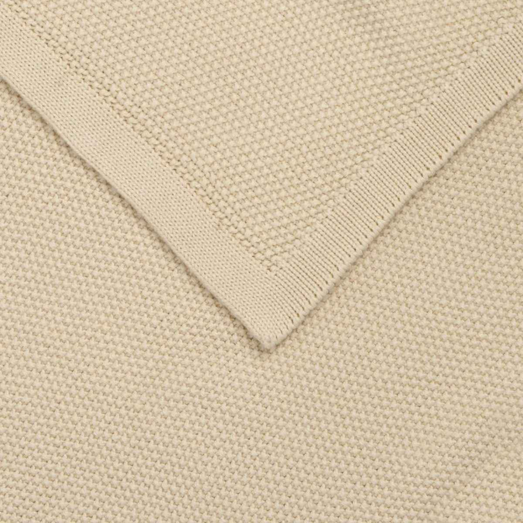 Close-up of a cream knitted blanket with a folded corner