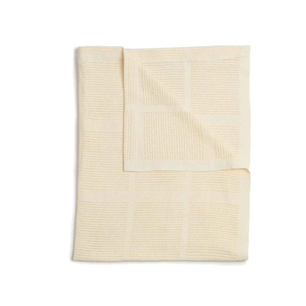 Folded beige pram blanket on a white background