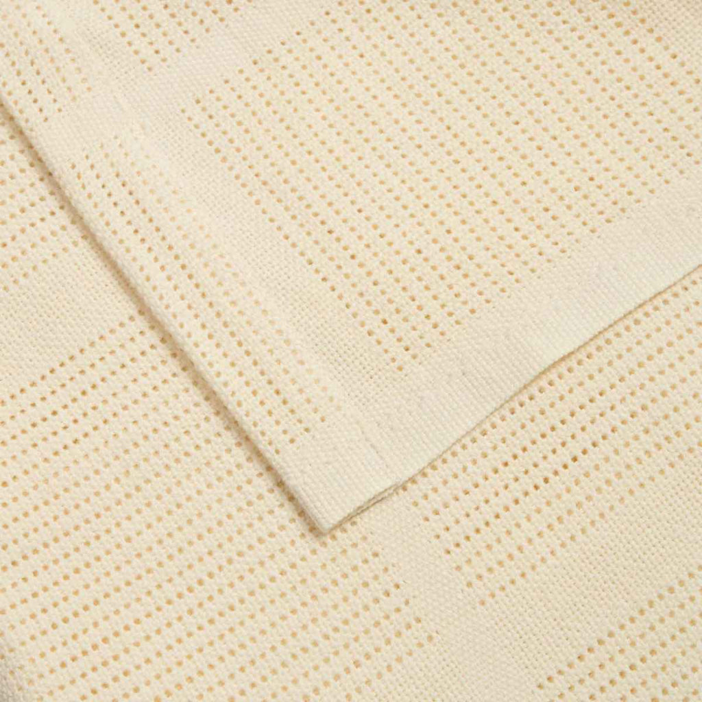 Close-up of a beige textured fabric blanket with a cellular pattern