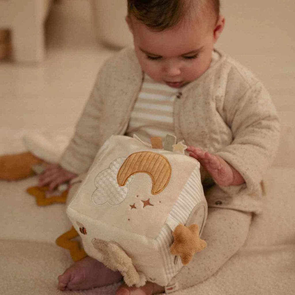 Baby playing with soft activity cube featuring stars and a moon.