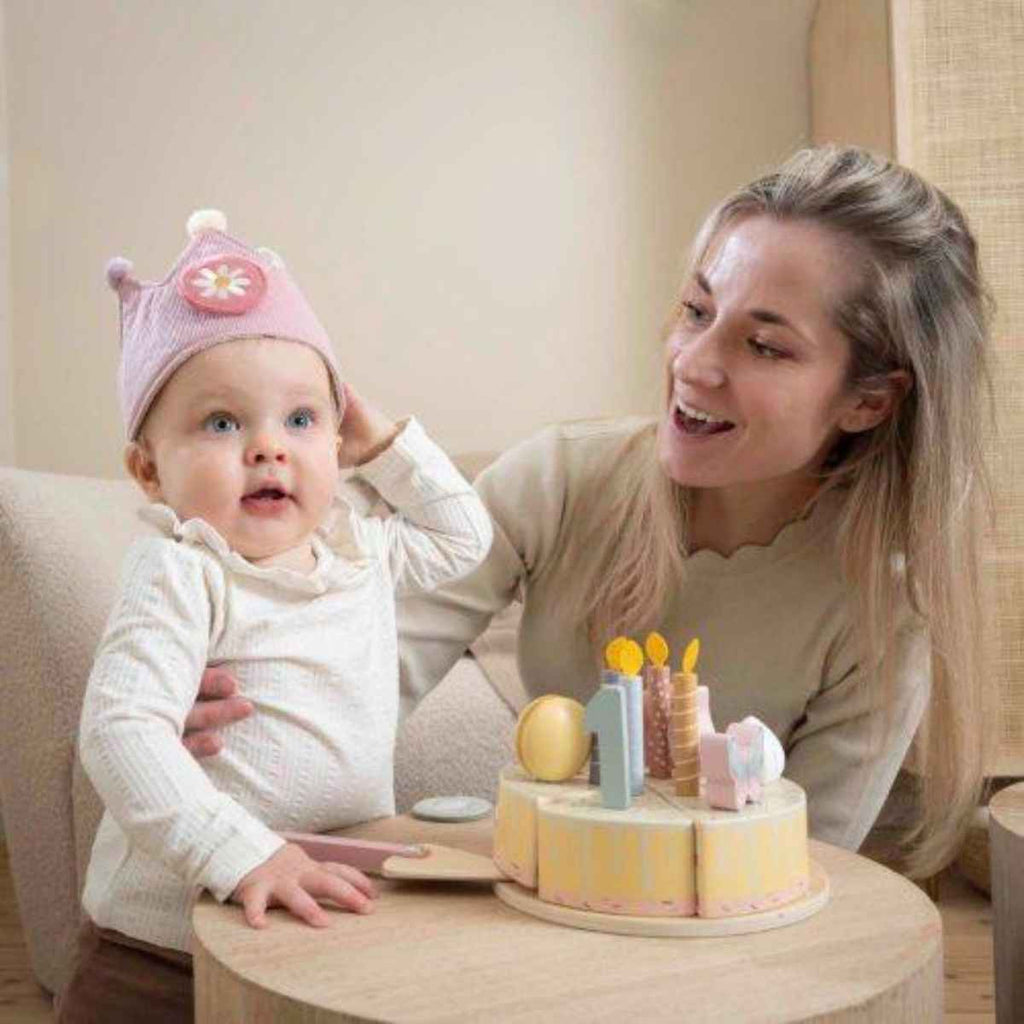 Woman and baby sitting together with a small wooden cake on a table