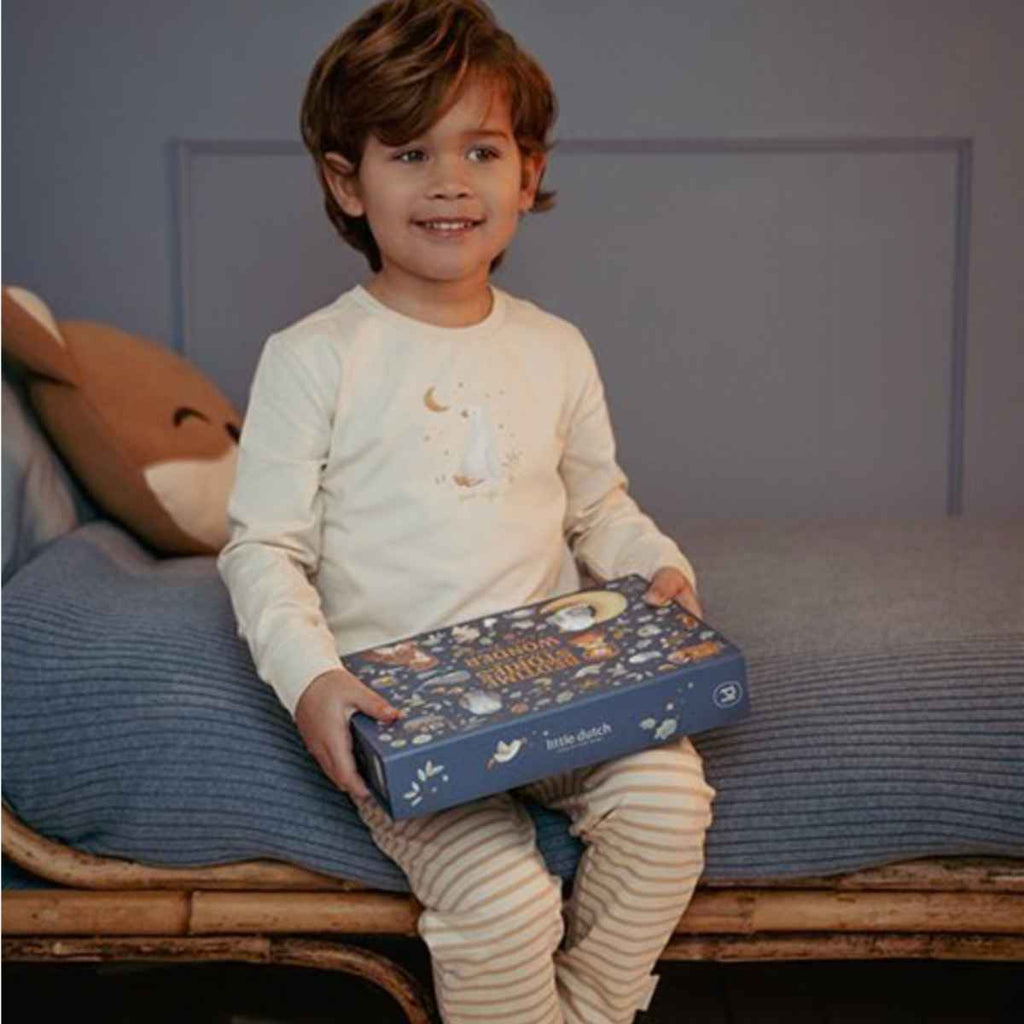 Child sitting on a bed holding a blue projector box with an animal design.