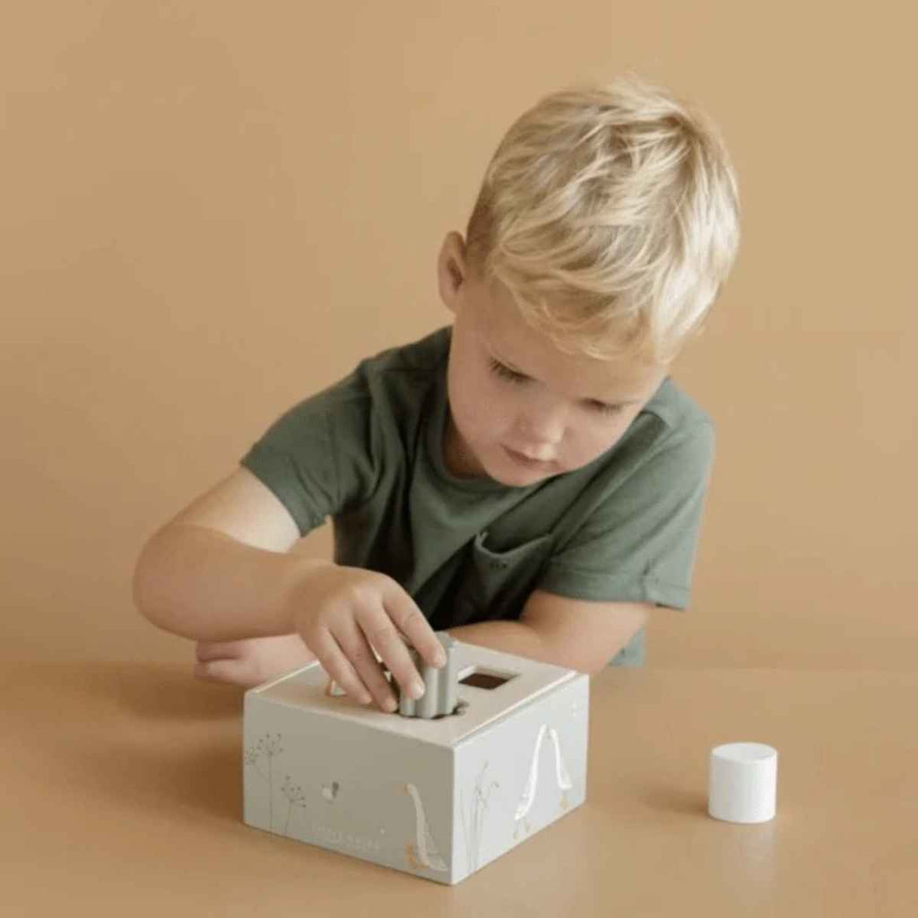 Child playing with a shape sorter toy on a beige background