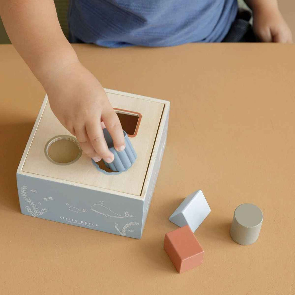 Child playing with a shape sorting toy on a brown surface