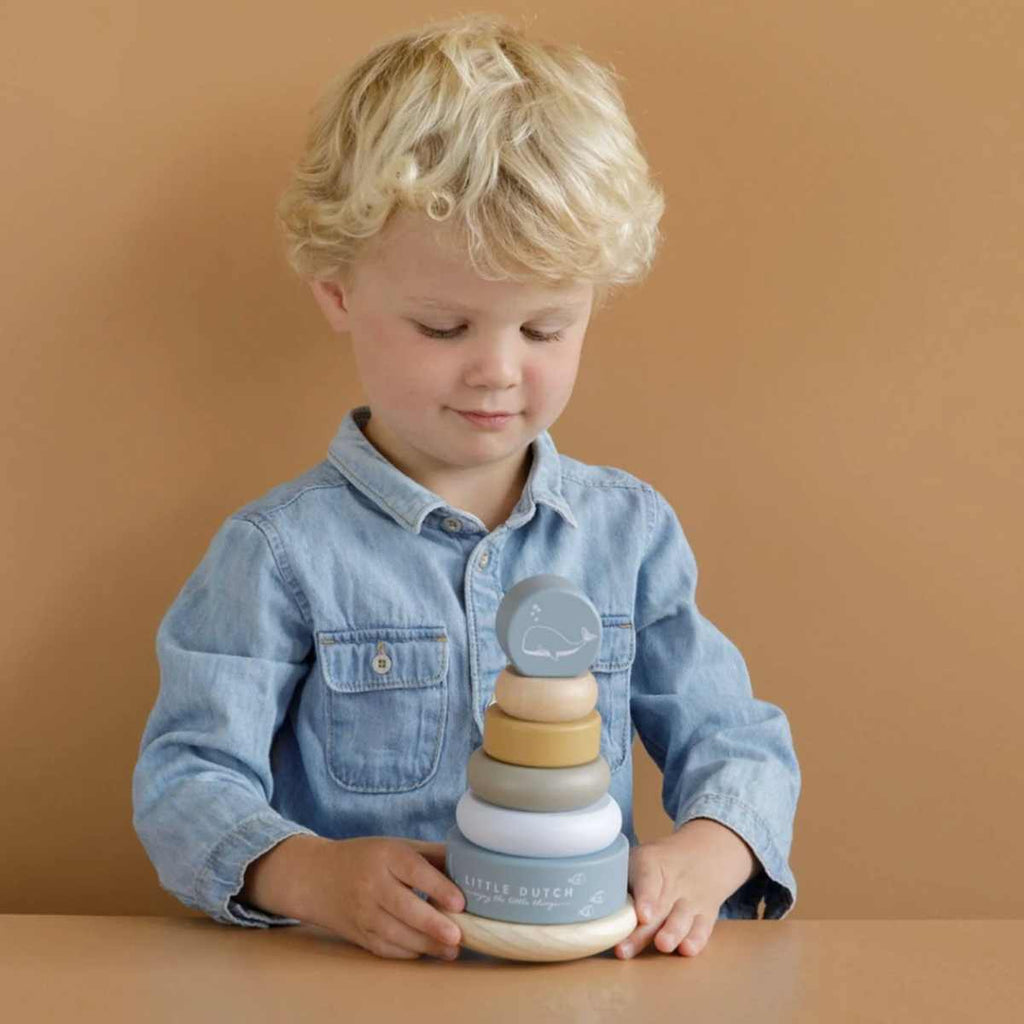 Child playing with a stack of wooden toys on a brown background