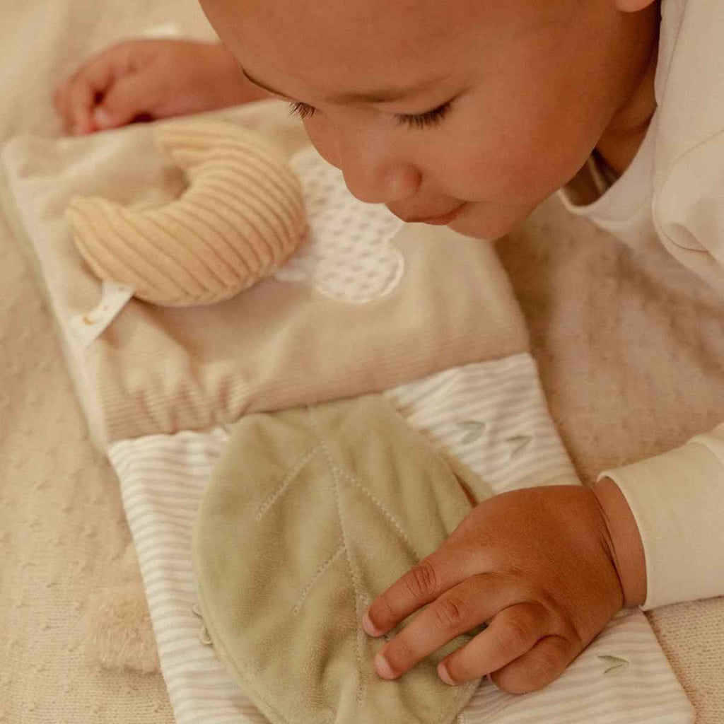 Child laying down with open activity book on a soft background.