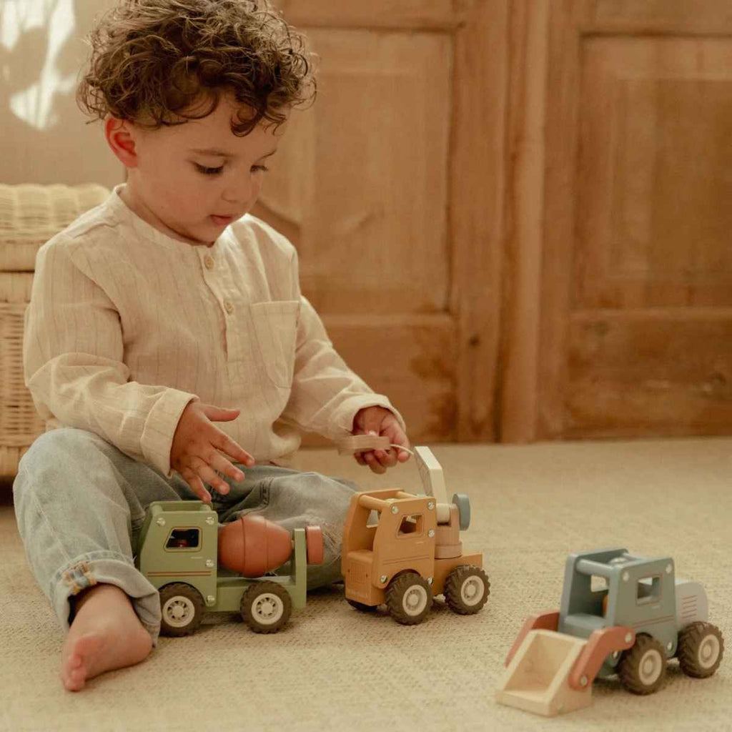 Child playing with wooden toy trucks on a carpeted floor