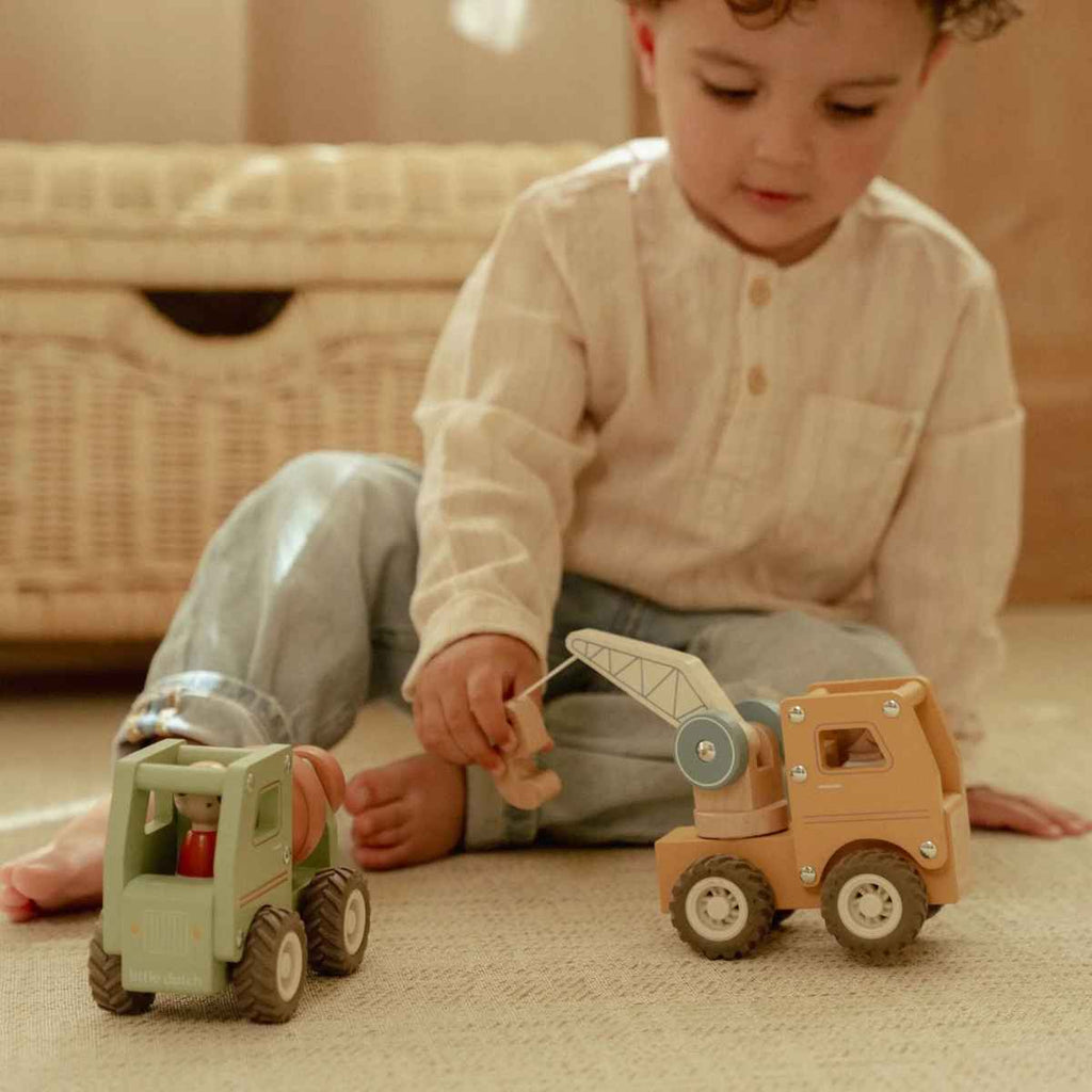 Child playing with toy crane on a carpeted floor