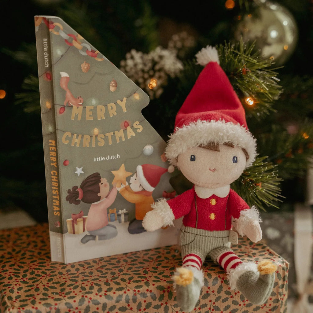 Christmas-themed book and toy figure with a Christmas tree in the background