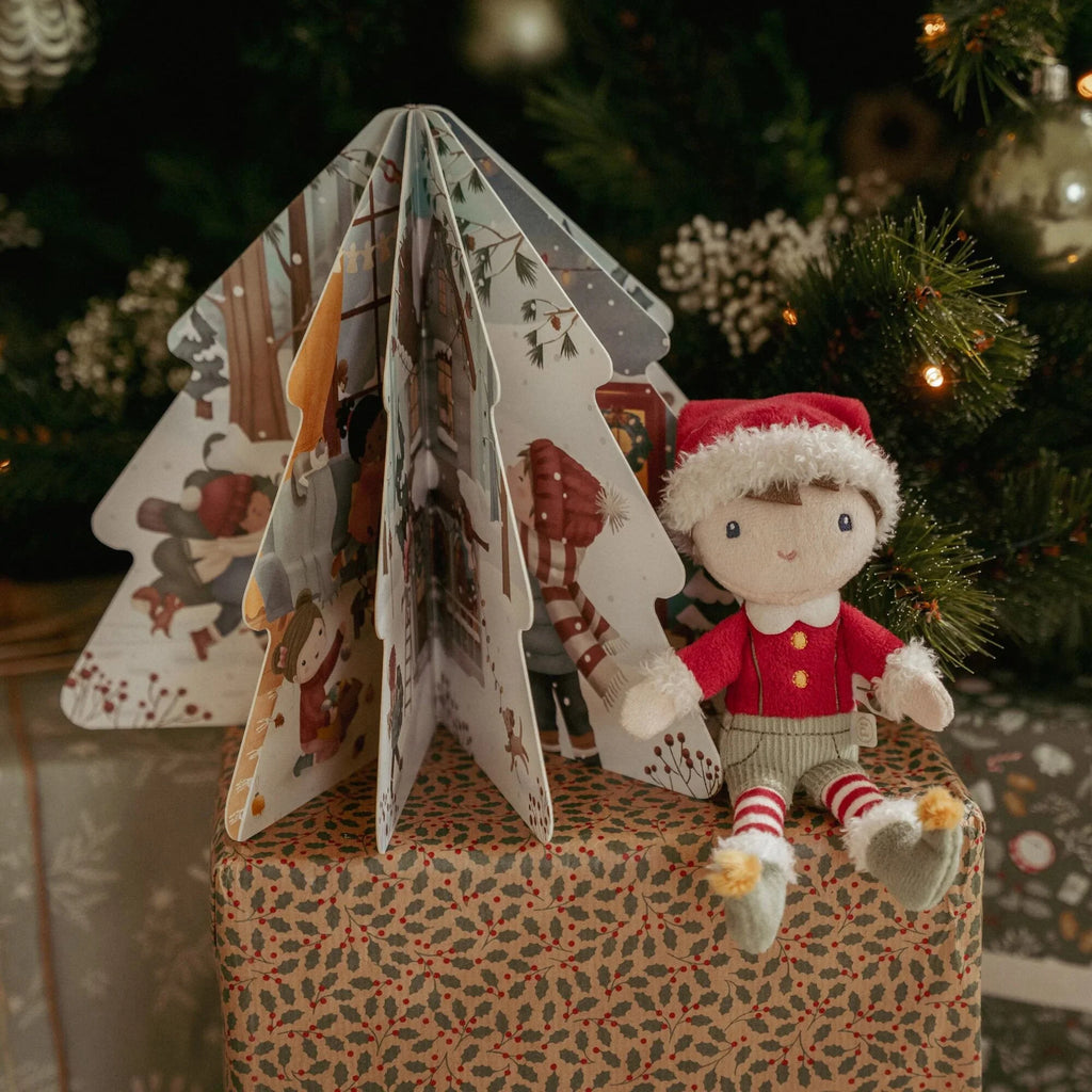 Christmas-themed book with a elf doll sitting on a wrapped present in front of a  Christmas tree.