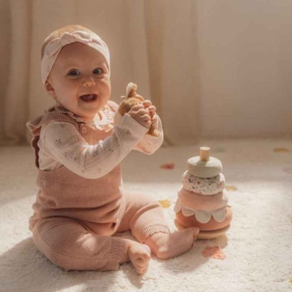 Baby holding soft deer head part of the rocking ring stacker. 