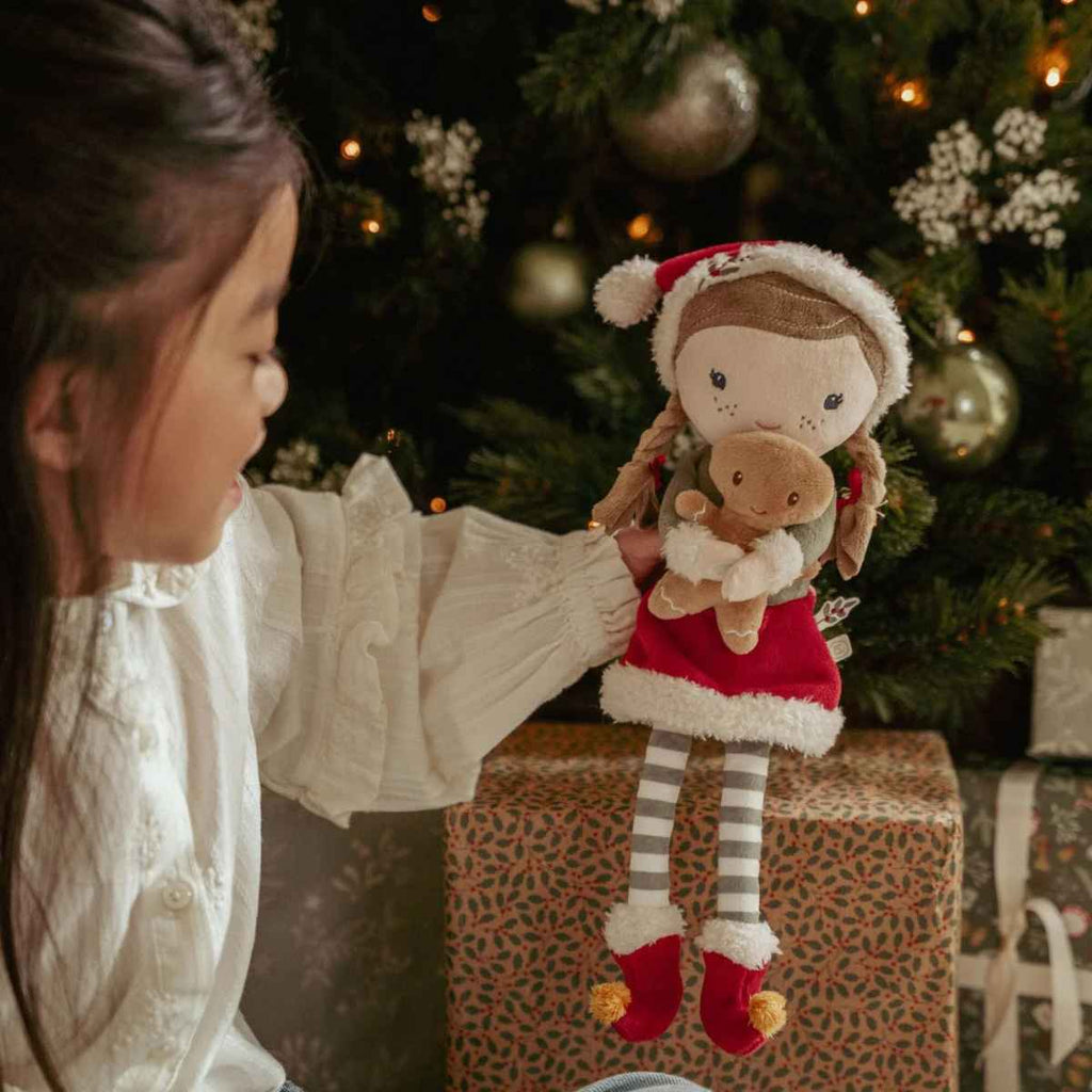 Child holding a plush toy with a Christmas tree and presents in the background