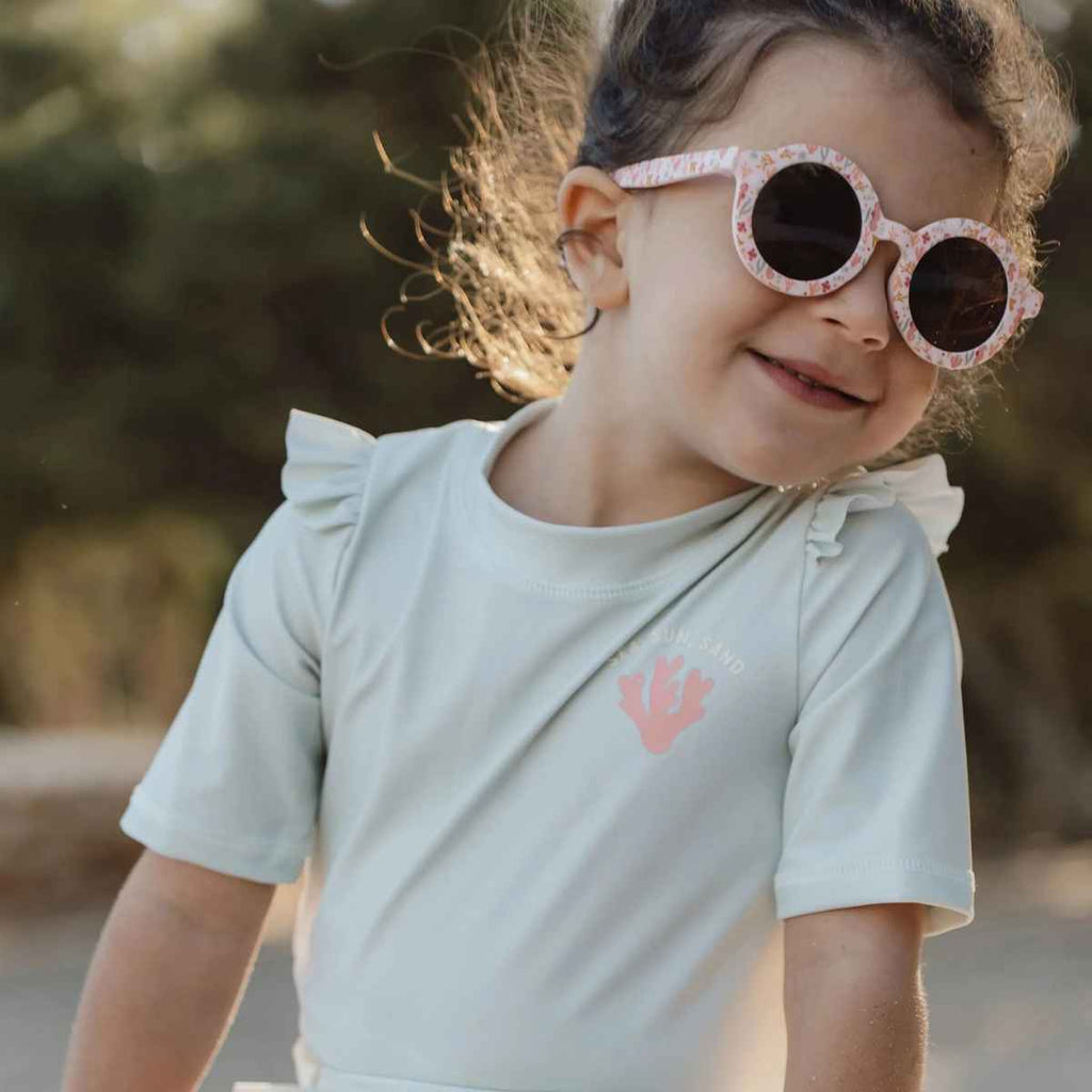 Child wearing pink sunglasses with a blurred nature background