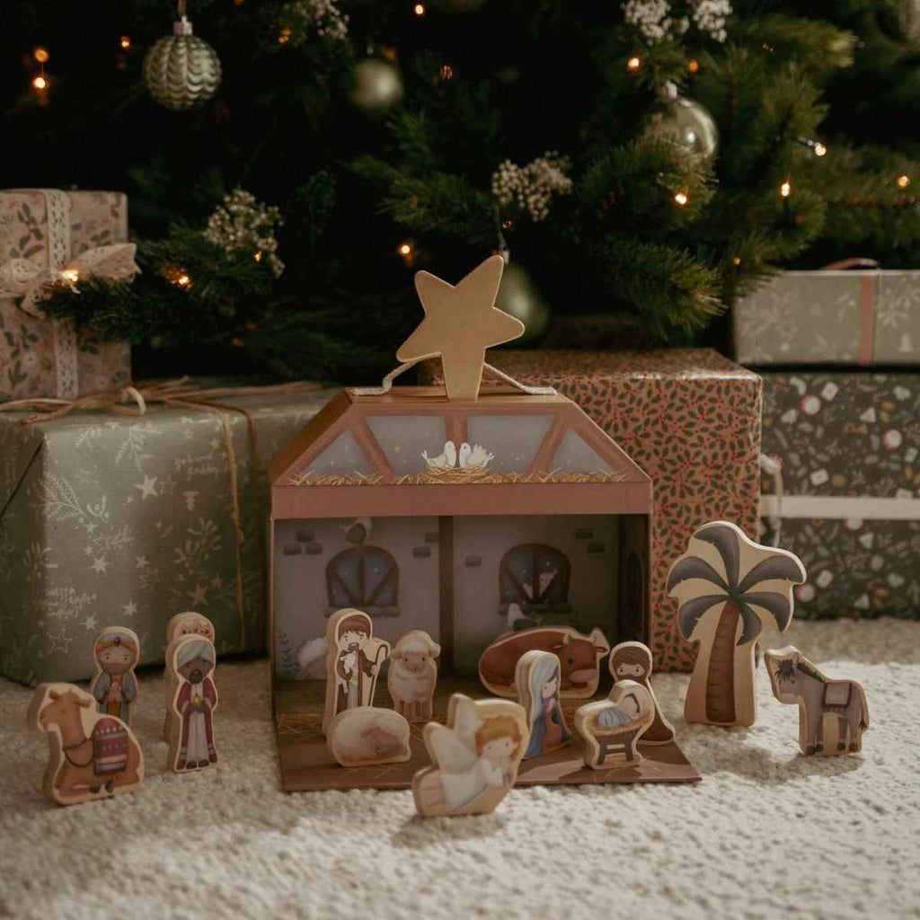Wooden nativity scene with a star on top, surrounded by Christmas decorations and presents.