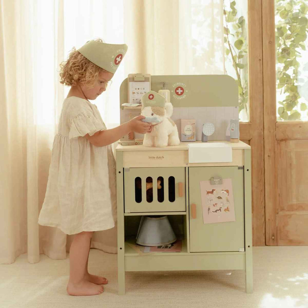 Child playing with plush cat Marley with a toy vet set in a bright room