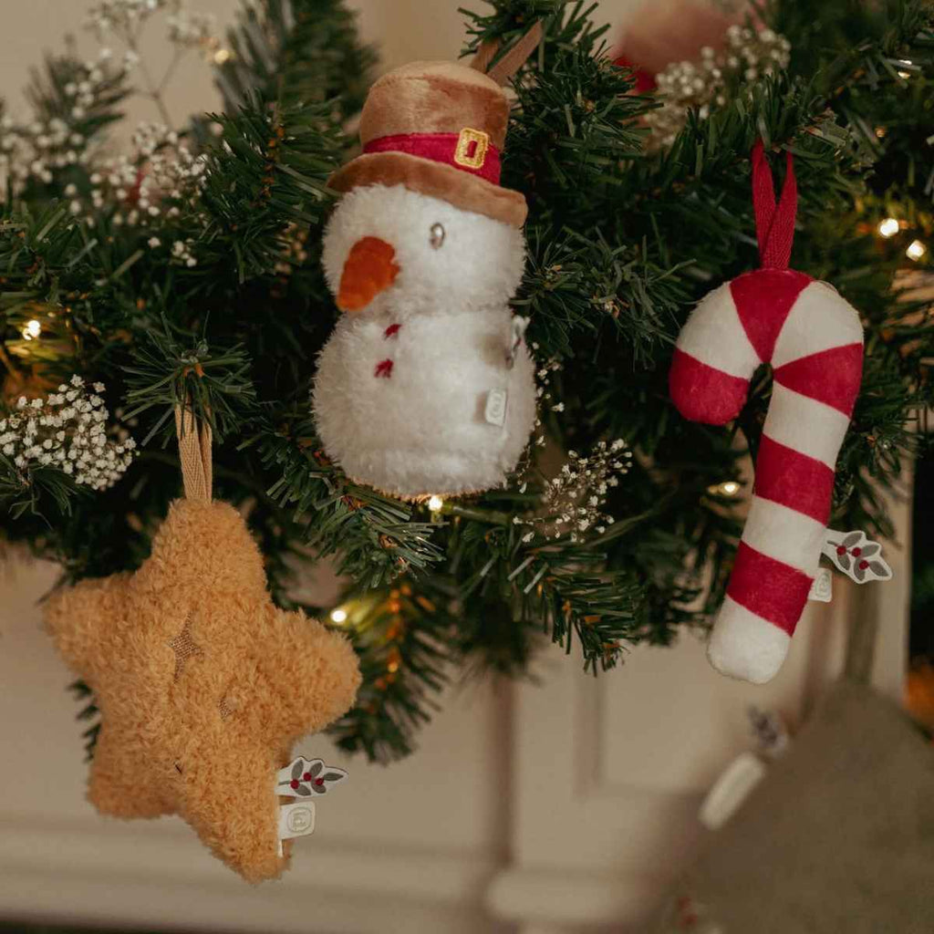 Decorative Christmas ornaments including a snowman, star, and candy cane hanging on a fireplace.