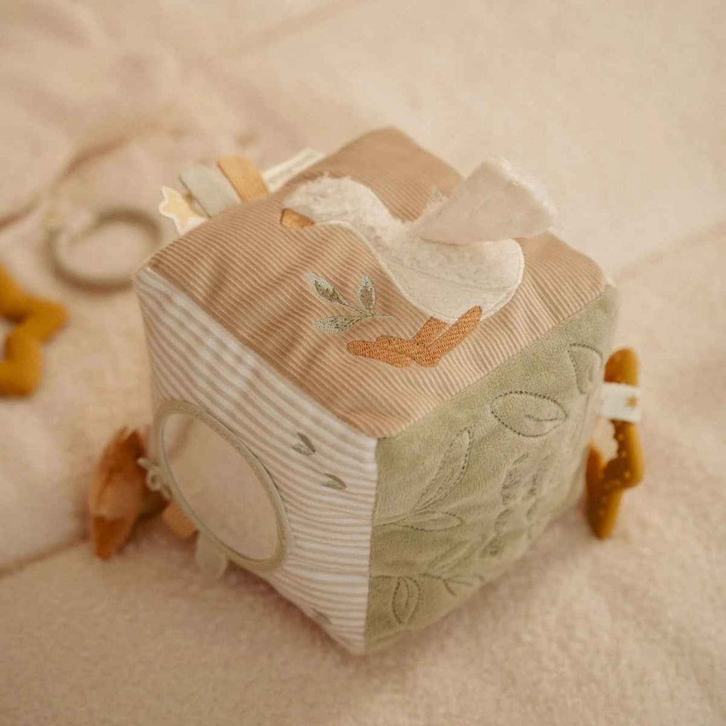 Fabric activity cube with animal and nature designs on a soft surface