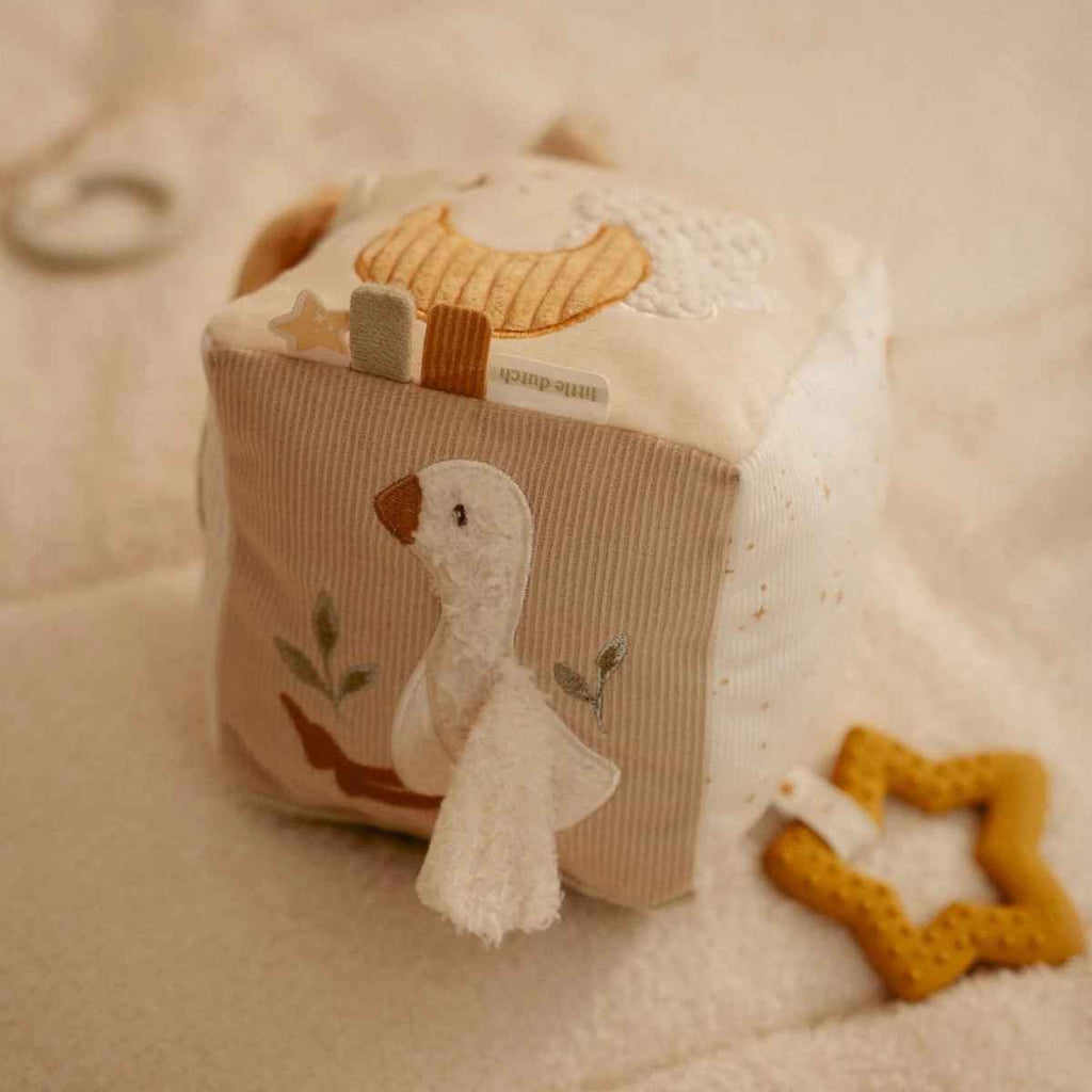 Soft activity cube with embroidered duck design on a soft beige background