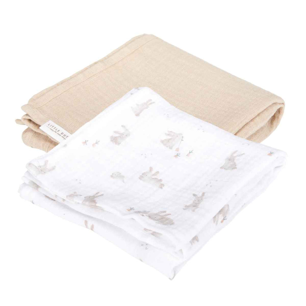 Two baby swaddles, one in a plain beige colour and the other in white with a bunny design.