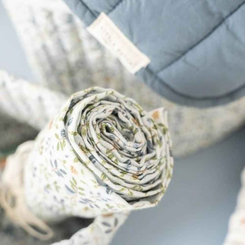 Rolled-up baby swaddle with floral pattern on a blurred background