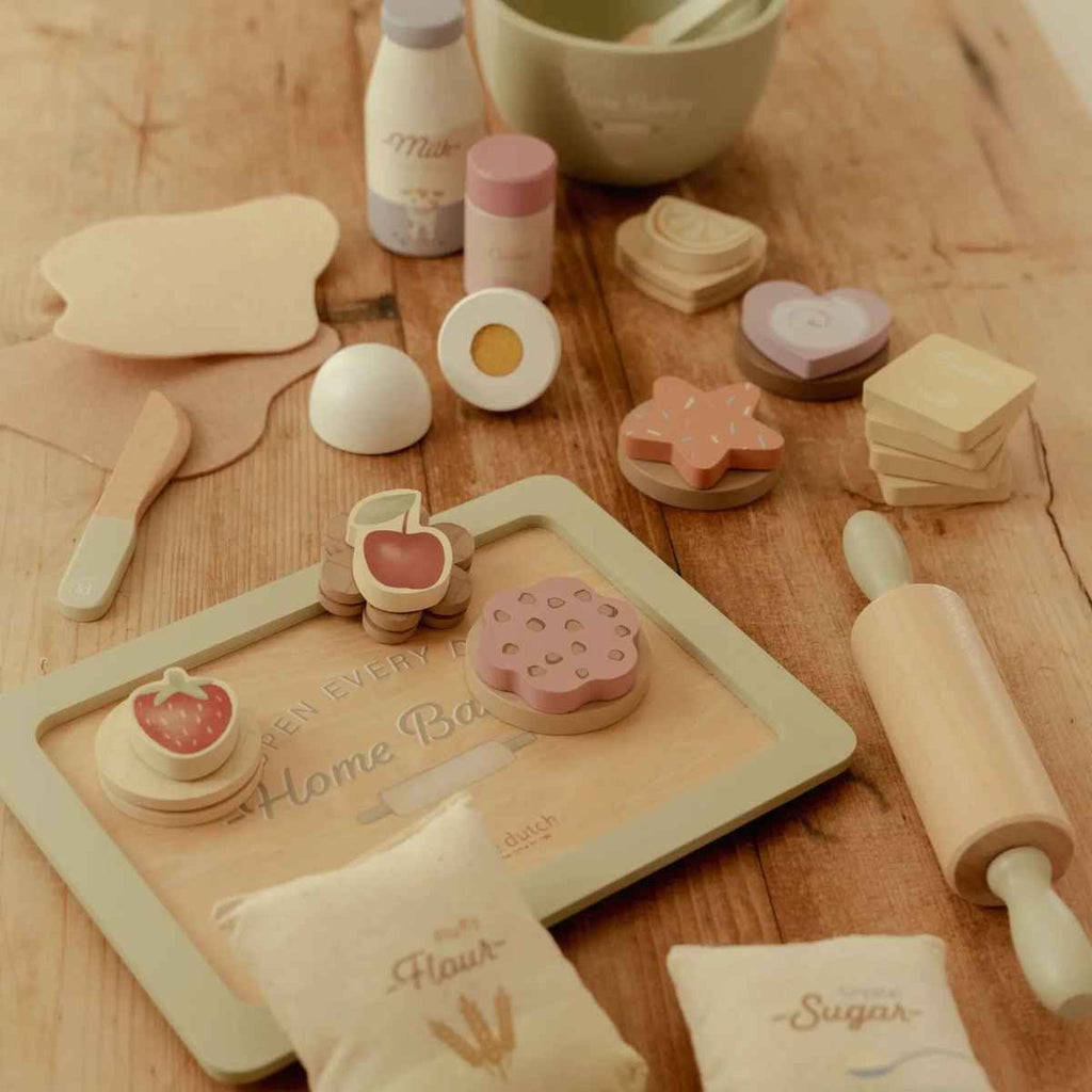 Wooden toy kitchen set on a wooden surface with various utensils and a wooden tray.