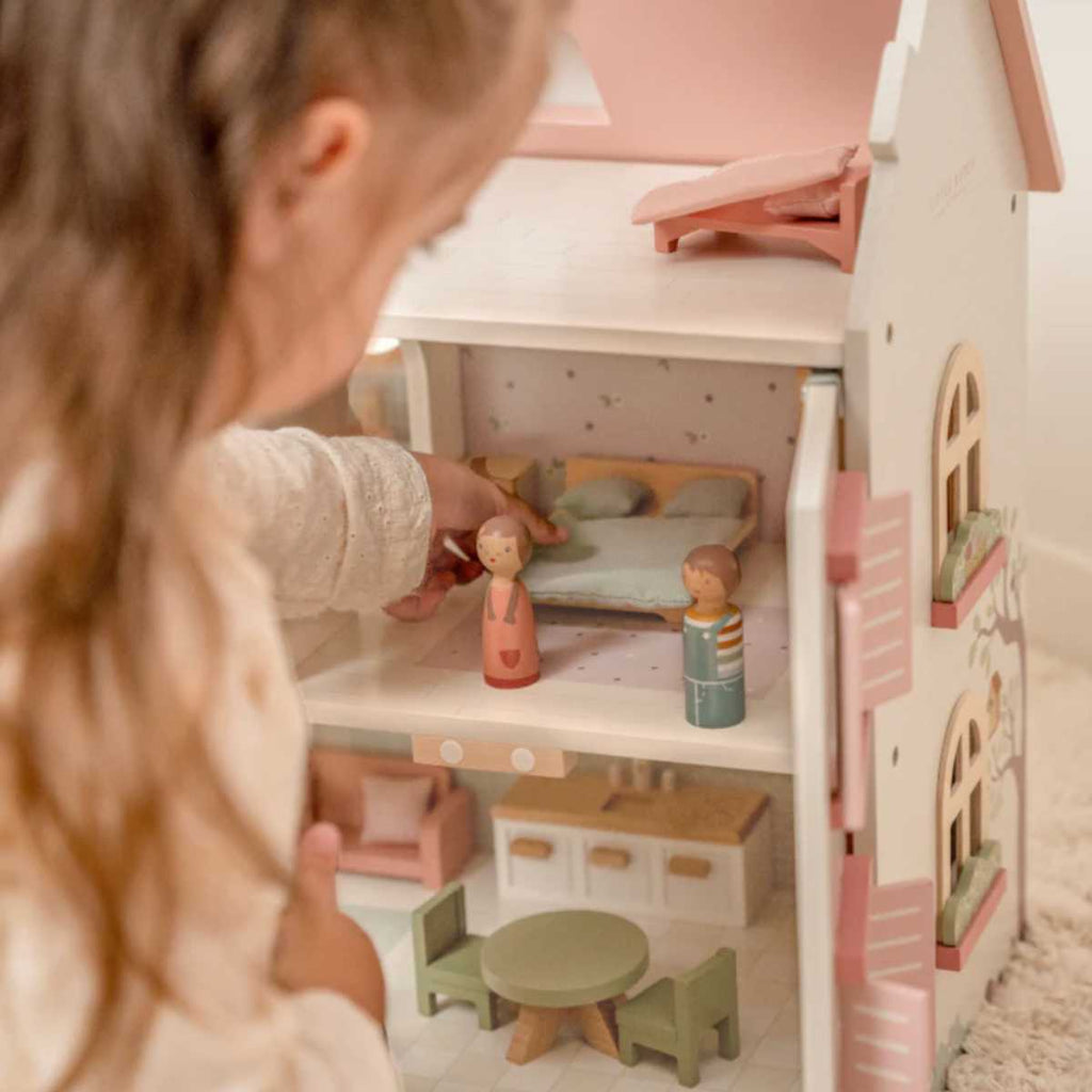 Child playing with a open dollhouse and dolls.