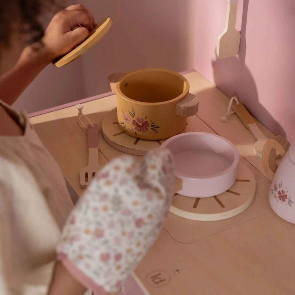 Children's play kitchen set with yellow pot, pink bowl, and floral-patterned mitt.