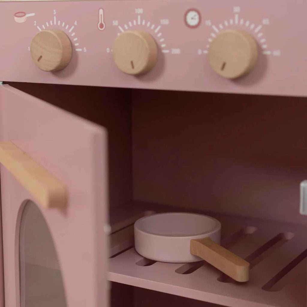 Pink toy oven with wooden knobs and a pan inside