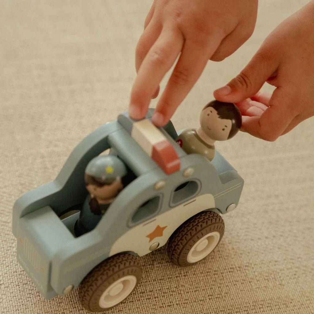 Toy police car with figures on a beige surface