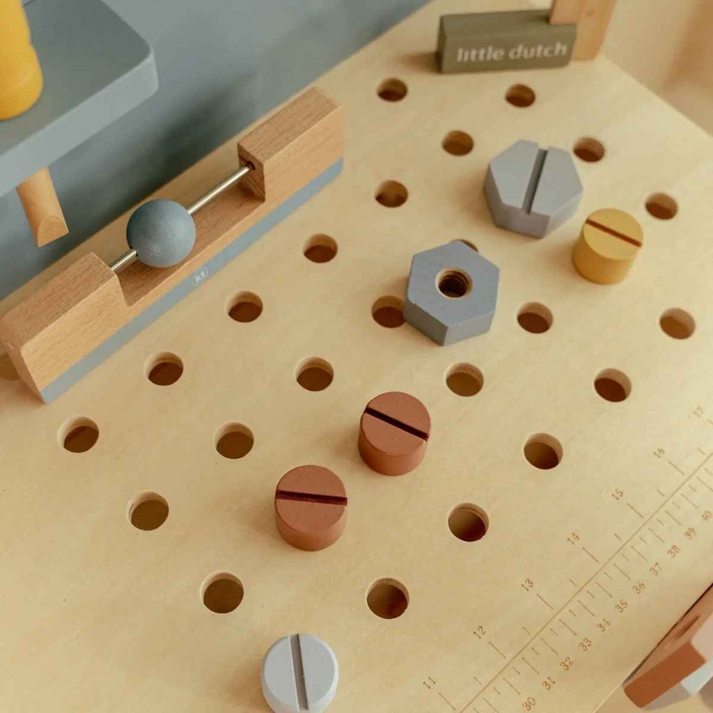 Wooden pegboard with various wooden tools on a worktop surface.