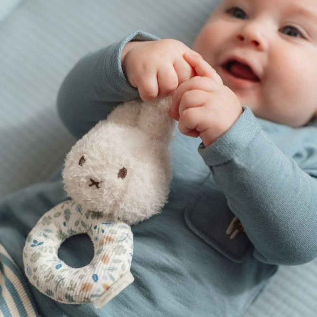 Baby holding a soft toy with a neutral background