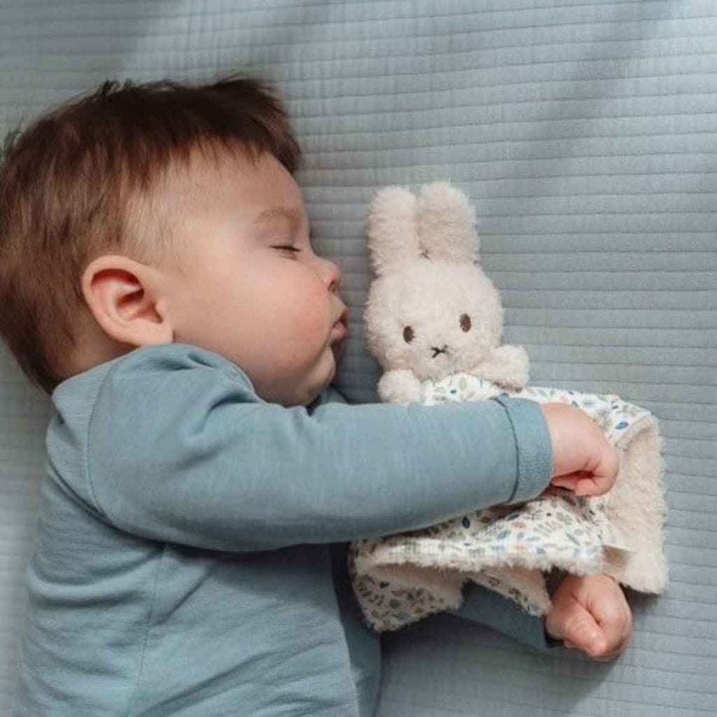 Child hugging a plush bunny cuddle cloth on a soft surface