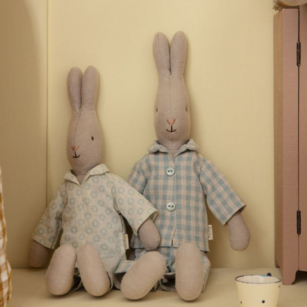 Maileg | Cream coloured bunny soft toy wearing a blue tartan Pyjama set | Bunny rested against a wall beside another Maileg bunny | Chocoloons 